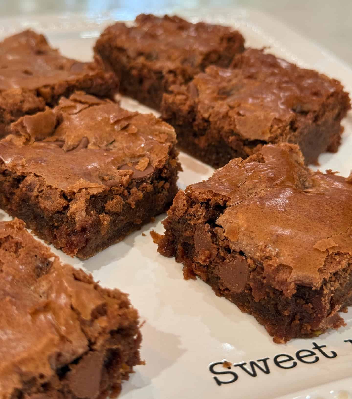 Best chocolate brownies recipe with extra chocolate chips cut on a white plate.