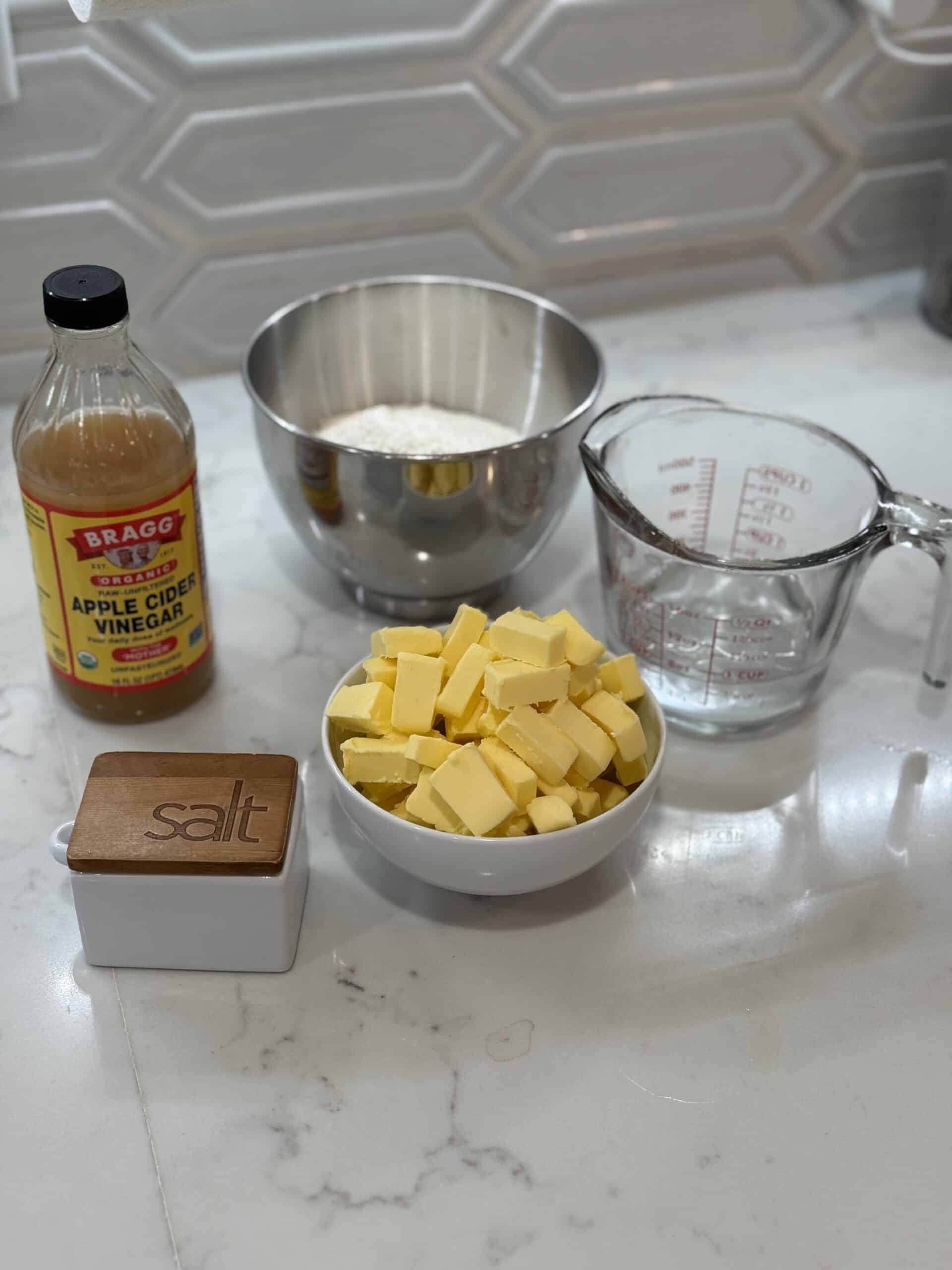 raw ingredients (cold water, apple cider vinegar, flour, butter, salt) sitting on the counter for making pie crust
