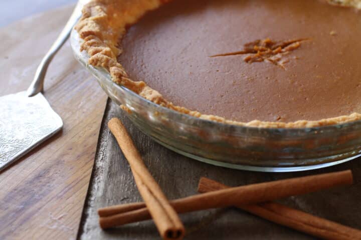 Homemade pumpkin pie on Thanksgiving table surrounded by fall decor