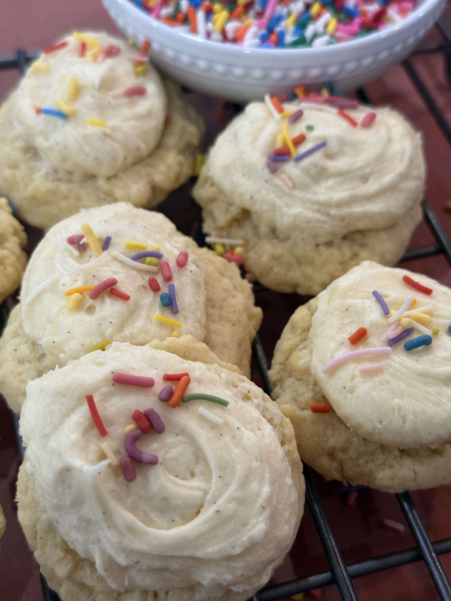 Homemade sugar cookies with frosting and sprinkles, finished soft and buttery on a cooling tray