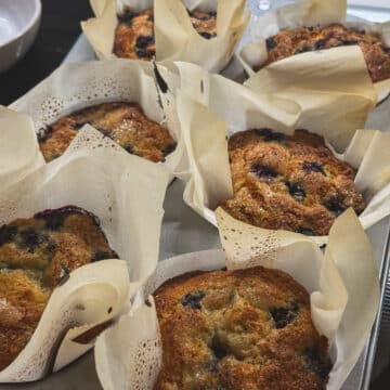 Classic blueberry muffins with golden tops and blueberries baked throughout